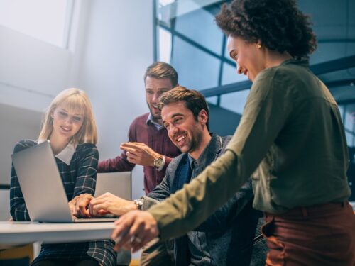 a team of four people looking at a laptop while they explore AI